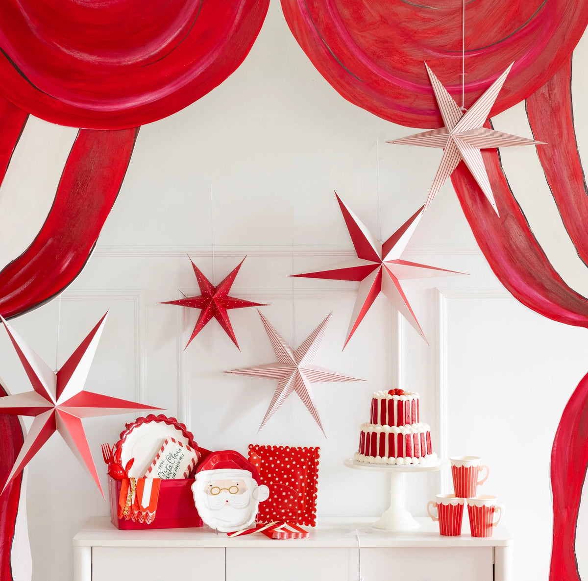 Red and white paper stars hanging above a dessert table against a red-and-white striped backdrop.