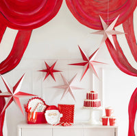 Red and white paper stars hanging above a dessert table against a red-and-white striped backdrop.