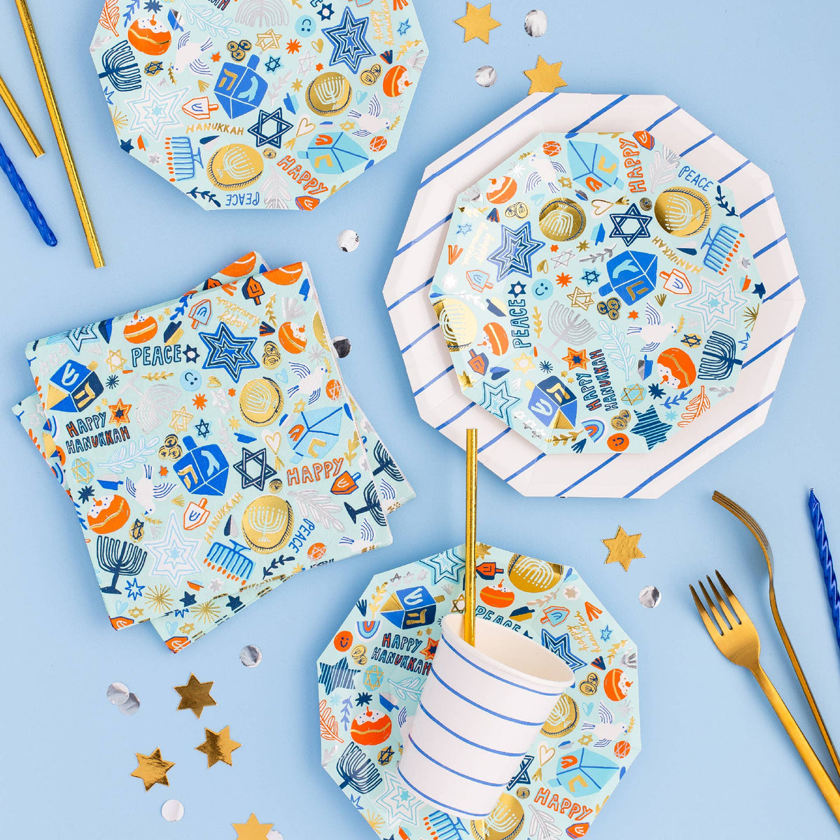 Festival of lights Hanukkah plates styled on a blue table with napkins and gelt