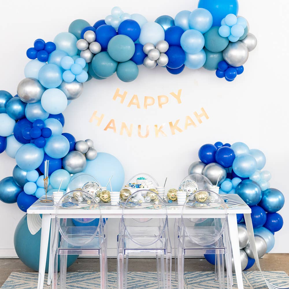 Star of David Hanukkah plates styled under a Happy Hanukkah balloon arch
