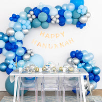 Star of David Hanukkah plates styled under a Happy Hanukkah balloon arch