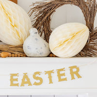 Happy Easter gold banner styled on a mantel with spring decor and honeycomb eggs