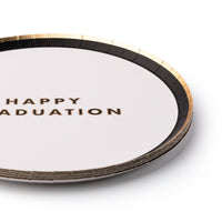 Stack of white graduation snack plates with gold lettering saying "Happy Graduation"