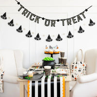 Six-foot puffy witch-hat banner hung above a kids’ Halloween dessert table decorated in black, white, and orange.