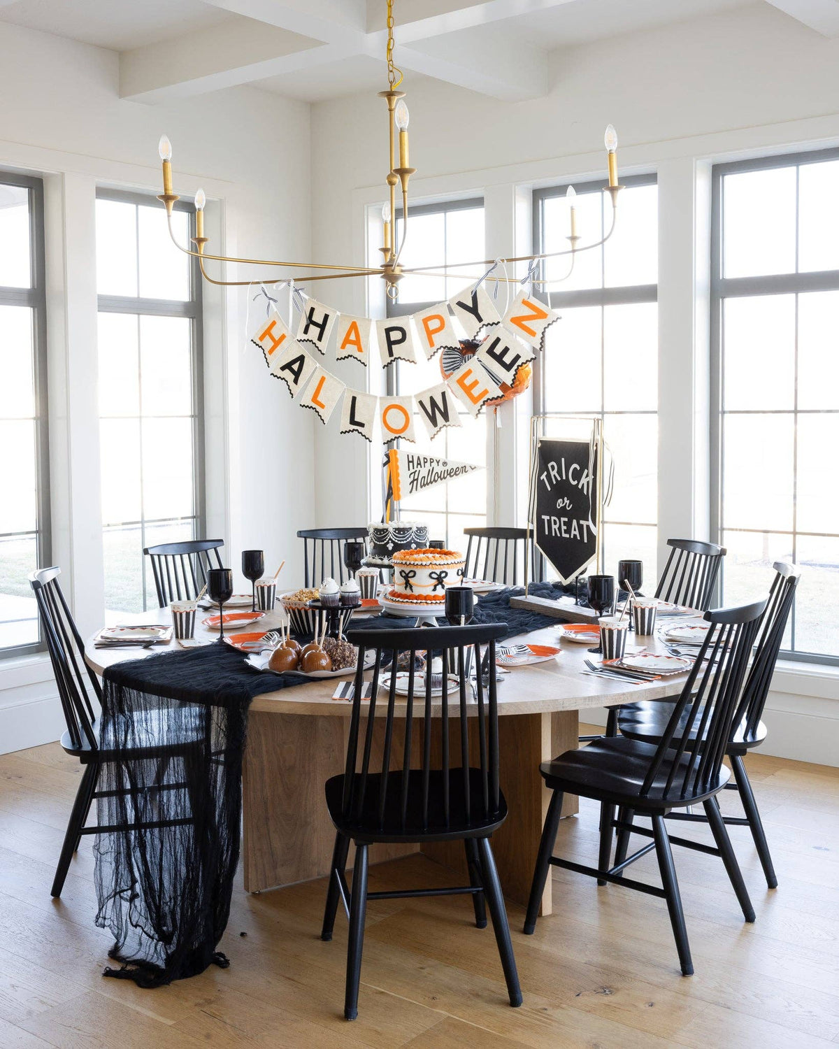 Dining room with Halloween decorations, including a 'Happy Halloween' banner and black chairs.