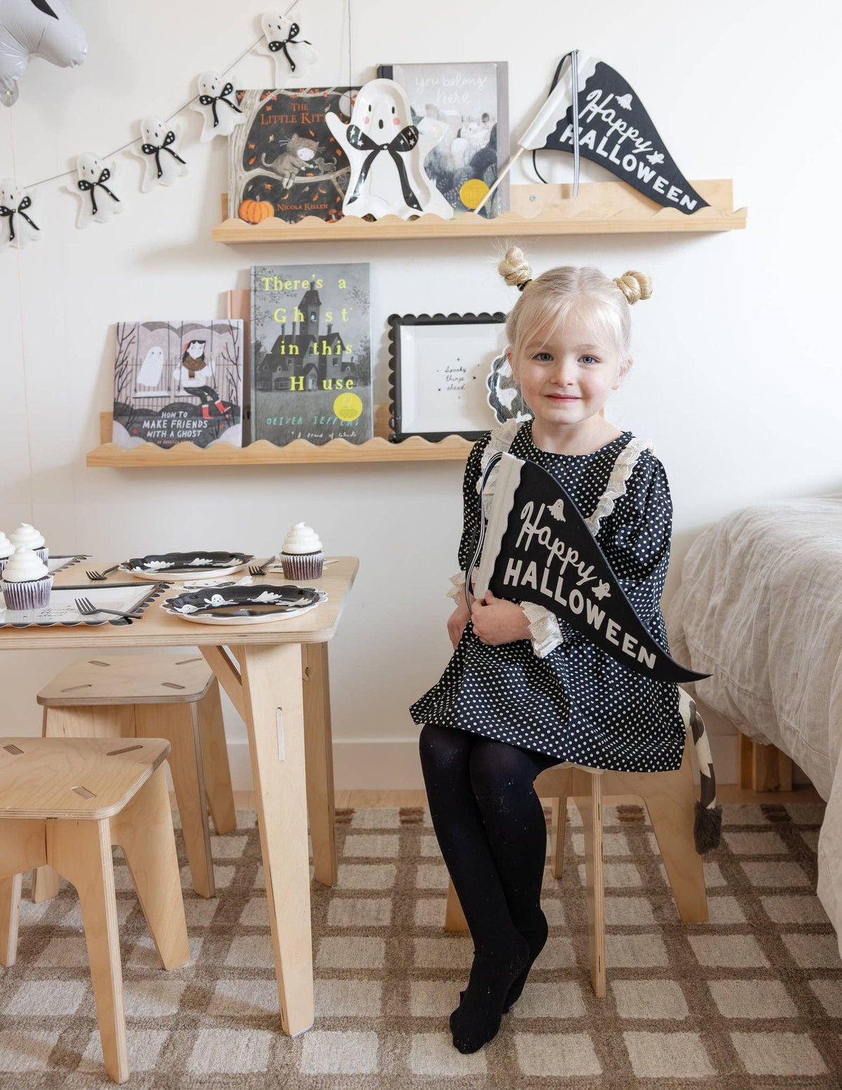 Child in a Halloween-themed room with decorations and a small table.