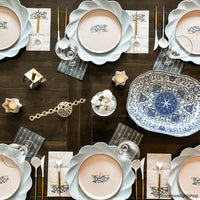 Hanukkah table with blue plates, floral menorah Hanukkah guest towels, and serving tray.