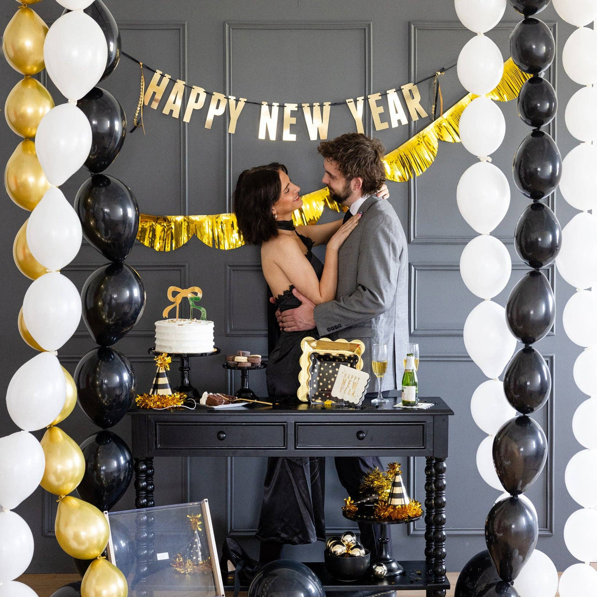Couple celebrating in front of Happy New Year banner backdrop
