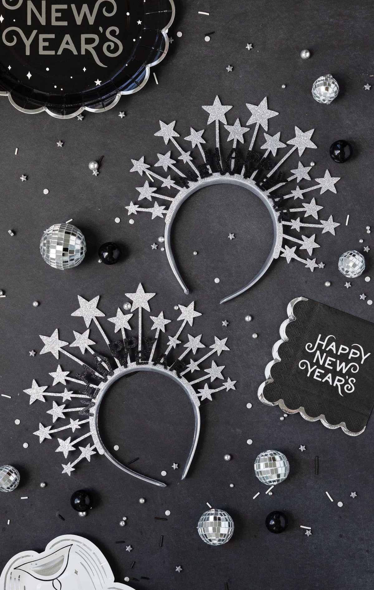 Black Happy New Year napkin styled on a New Year’s Eve table with star headbands and disco balls