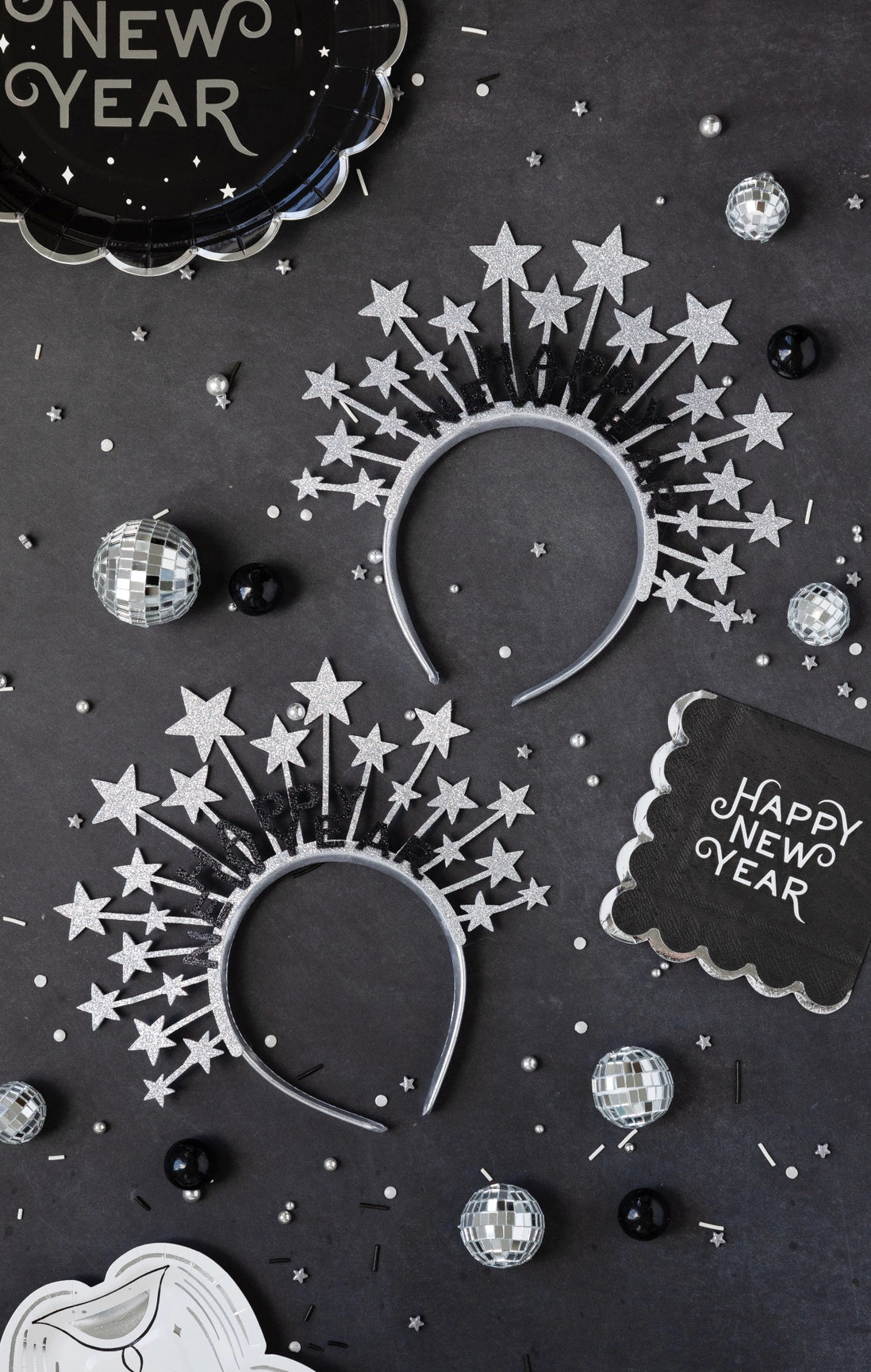 Black Happy New Year plates styled on a table with star headbands and disco balls
