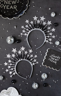 Black Happy New Year plates styled on a table with star headbands and disco balls
