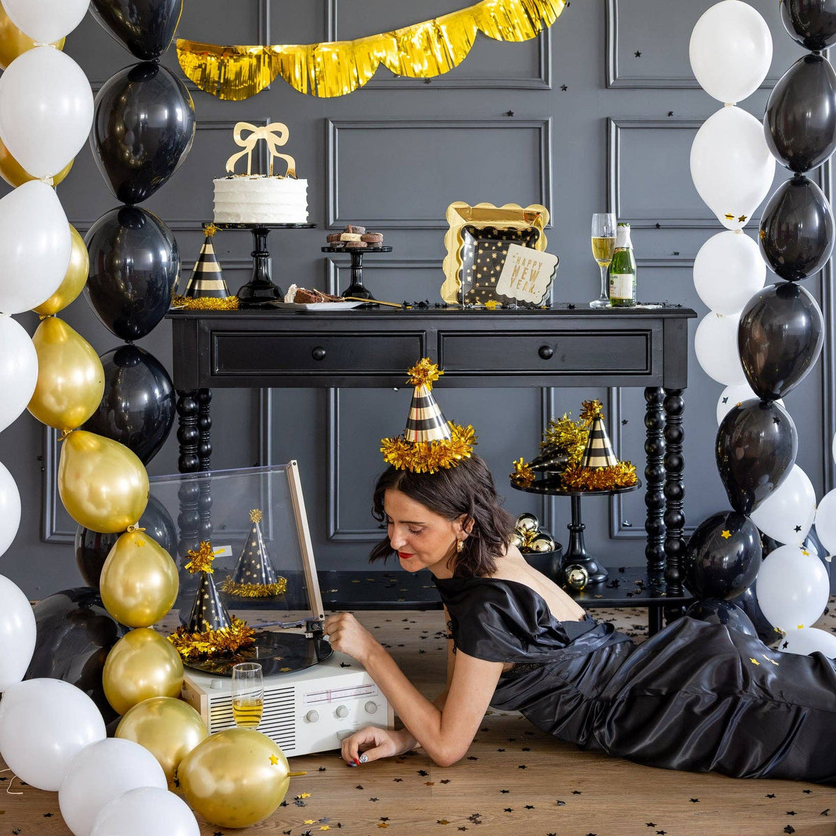 New Year's Eve party setup with black, gold, and white decorations featuring the cocktail napkin