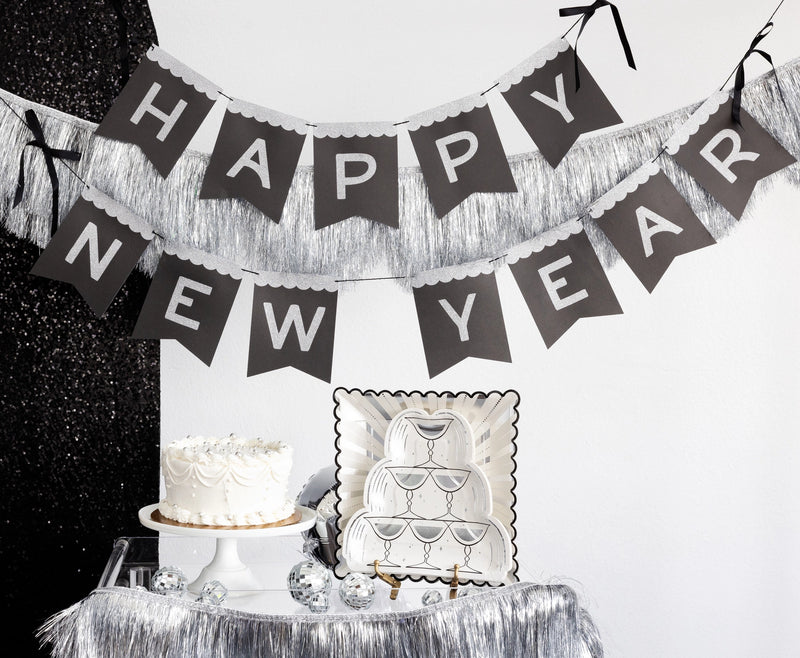 Happy New Year glitter banner hung above a styled dessert table with cake and plates