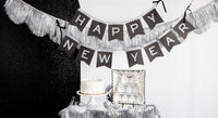 Happy New Year glitter banner styled above a New Year’s Eve dessert table