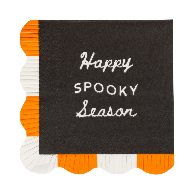 A single black cocktail napkin laid flat on a white background, "Happy Spooky Season" in cream lettering across the face, with two sides finished in an orange-and-white fringed scalloped border. Clean overhead product shot.