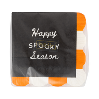 Front of the retail package: the top black napkin reads "Happy Spooky Season" in cream script and block capitals with a small gold brand sticker centered, and the orange-and-cream fringe edge peeks out at the right. Straight-on packaging shot.