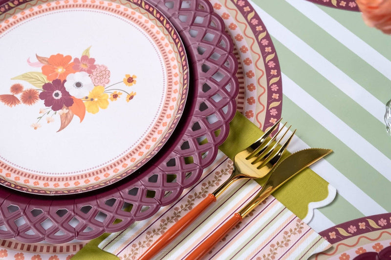 Folded harvest floral cocktail napkin on a plain surface showing the floral vine and autumn stripe pattern.