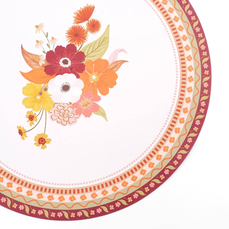 Angled overhead of the harvest floral placemat showing the off-center bouquet and detailed patterned border on the neutral base.