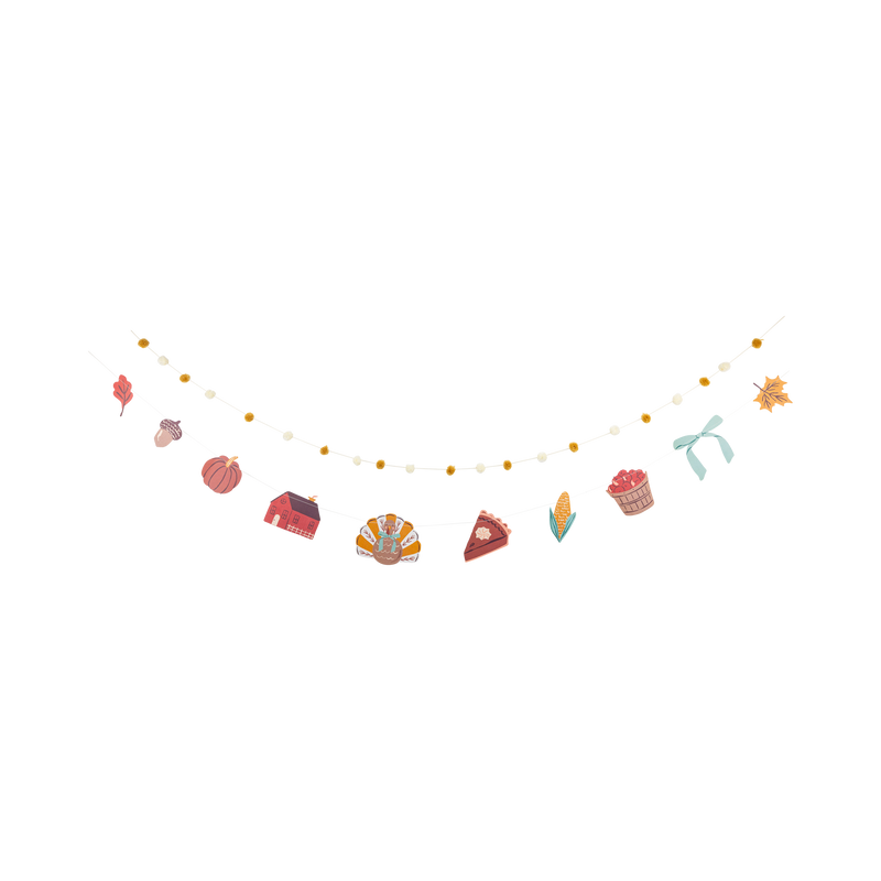Harvest banner with colorful illustrated paper icons and pom poms on cream thread, laid flat.