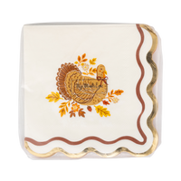 Stack of harvest turkey cocktail napkins showing the turkey illustration and wavy orange edge from an angled view.