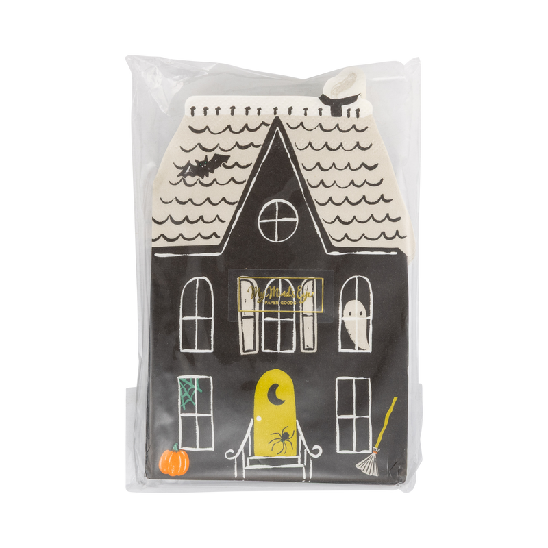 Front of the retail package: the top haunted house napkin face-up with a small gold brand sticker, showing the black mansion with arched white windows, a ghost, a bat, green spiderweb, broom, pumpkin, and yellow crescent-moon door. Straight-on packaging shot.