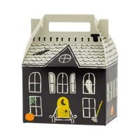 Single assembled haunted house box on a white background, three-quarter angle showing the front facade with arched windows, ghost, yellow door, pumpkin, broom, and green spiderweb, plus the side wall, cream shingled roof, and cut-out carry handle. Clean hero product shot.