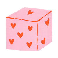 Pink dice-shaped napkin with red heart pips.