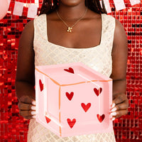 Woman holding heart dice plate in a Valentine-themed backdrop.