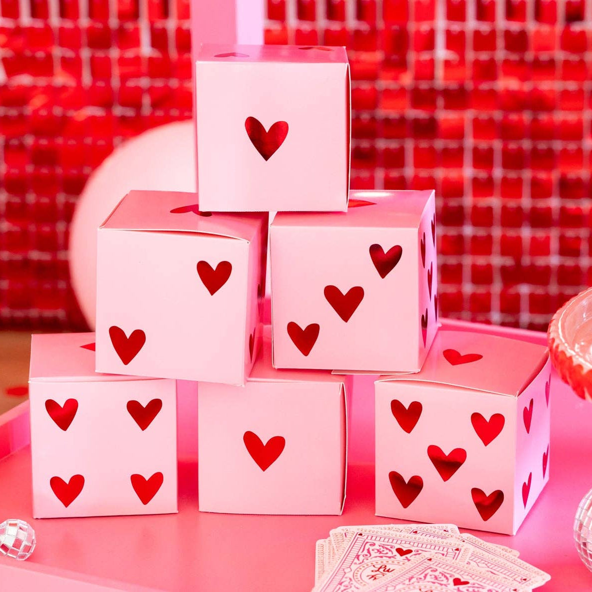 Stacked pink heart dice treat boxes displayed on a Valentine party table