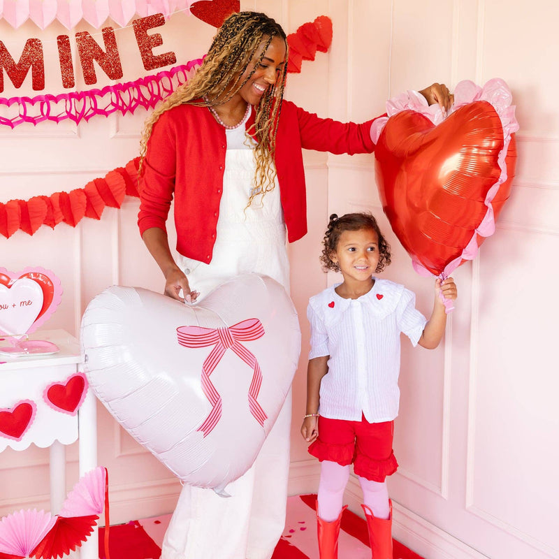 Large heart balloon with printed bow held at a Valentine setup