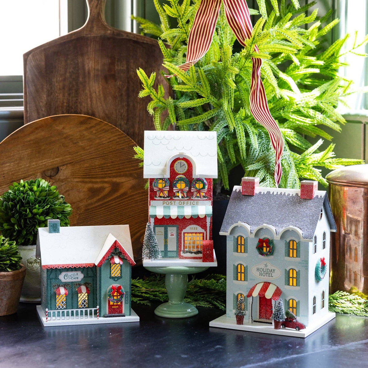 Three light up Christmas village buildings styled together with holiday hotel on right