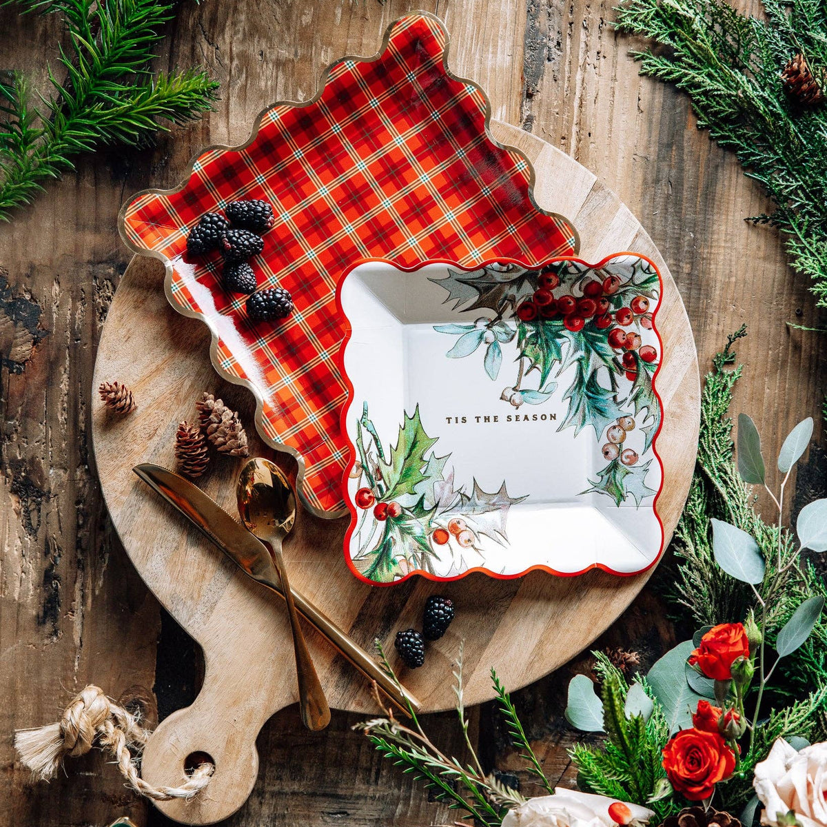 Holiday table setting with holly and red plaid scalloped plates on a wooden board