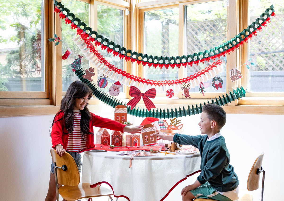 A room decorated with the honeycomb garlands strung across the wall with children opening gifts.