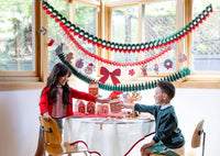 A room decorated with the honeycomb garlands strung across the wall with children opening gifts.