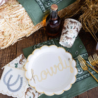 Howdy paper plate styled on rustic wood table with cowboy party cups and bandana napkins
