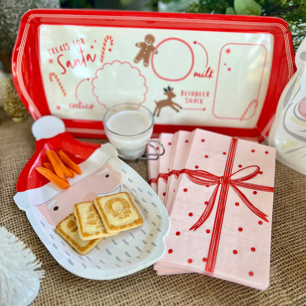 Paper Christmas napkins shaped like a pink wrapped gift with a red bow.