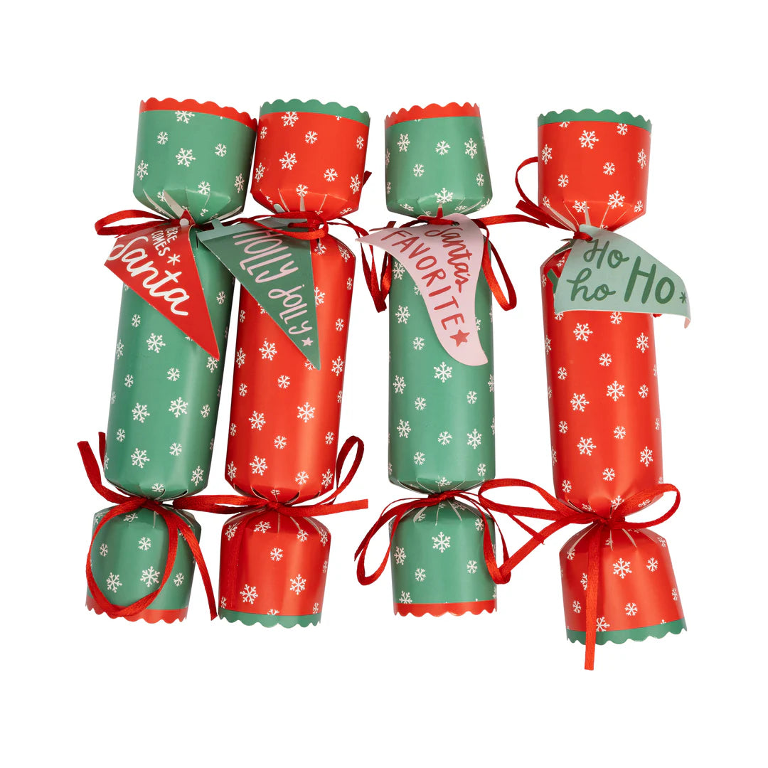 Isolated set of four assembled Christmas crackers showing the alternating red and green snowflakes design and paper tags.