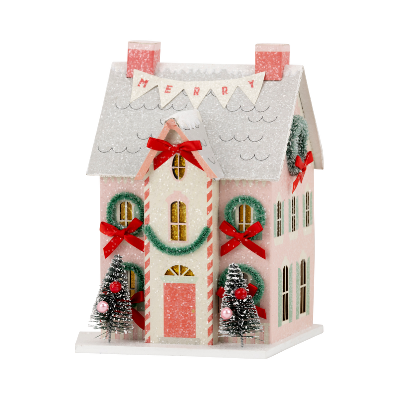 Close-up of the lighted Christmas village house featuring a "MERRY" banner and red bows, perfect for retro Christmas decor.