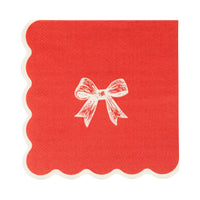 Isolated view of a single red paper cocktail napkin with a white illustrated bow and scalloped edge.