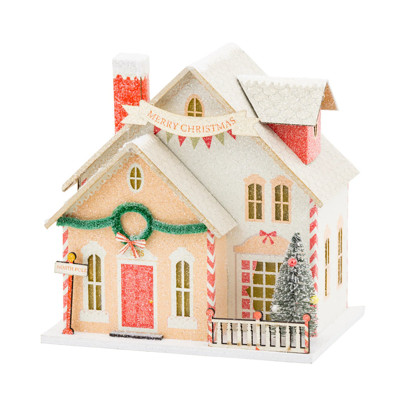 Isolated view of the Santa's House village piece, showing the "Merry Christmas" banner and glittery details.
