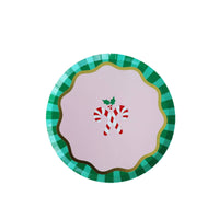 Round kids Christmas dessert plate with a candy cane and holly motif on a pink center, framed by a green-and-white striped scalloped rim, overhead view on white background.