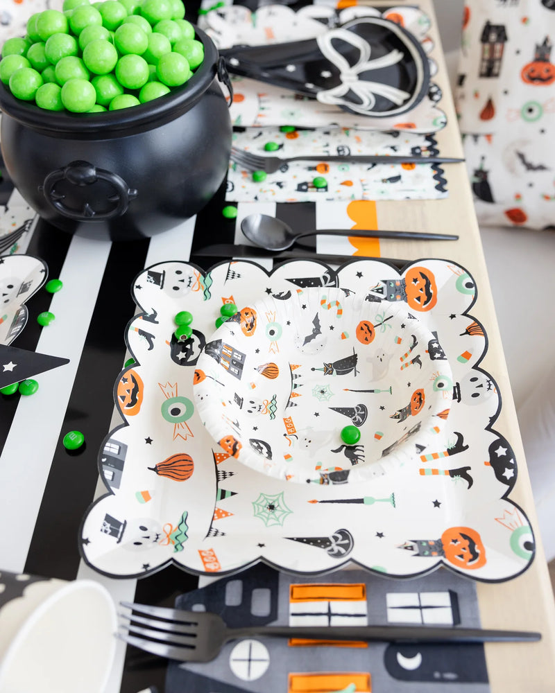  Overhead view of a kids’ place setting with the Halloween bowl nested inside a coordinating scalloped dinner plate on a black-and-white striped runner.