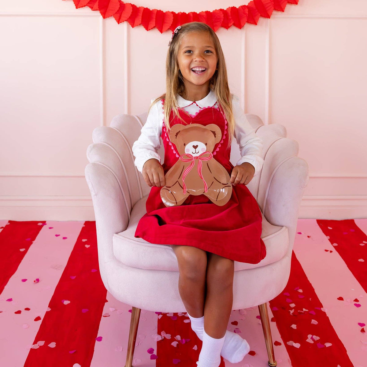 Child smiling while holding teddy bear plate at party