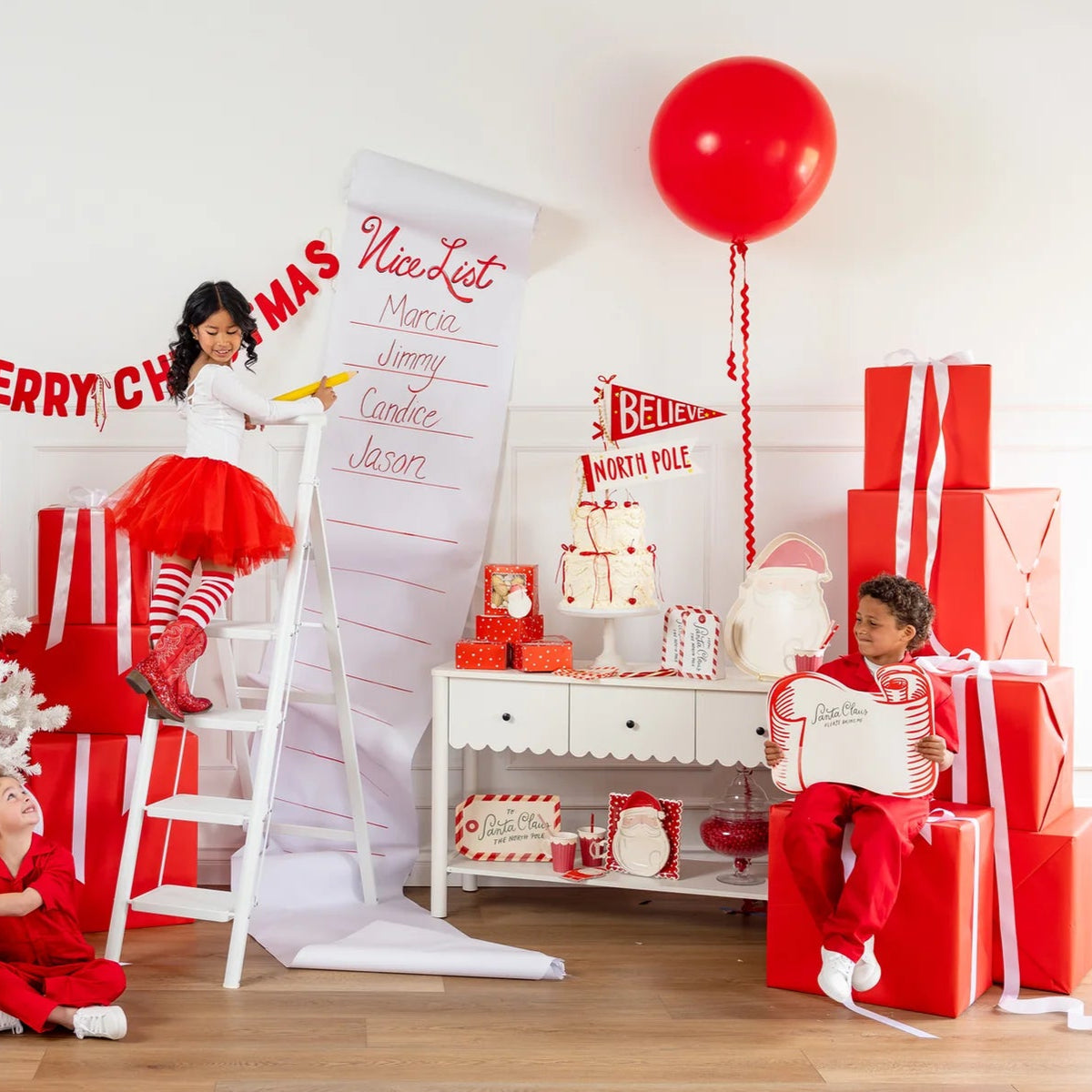 Two children playing next to a giant Nice List scroll and a boy holding the large Santa placemats in a festive room.