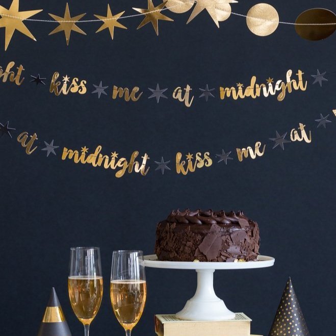 Gold Kiss Me at Midnight letter banner hung against a wall