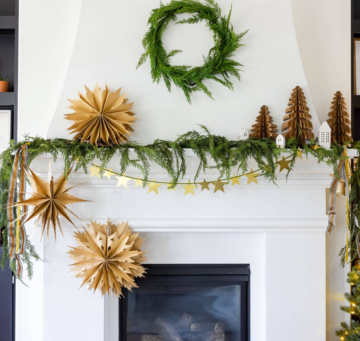 Kraft paper Christmas tree styled on a mantel with paper fans and a star garland