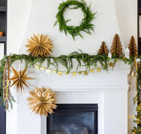 Kraft paper Christmas tree styled on a mantel with paper fans and a star garland