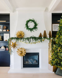 Kraft paper Christmas trees styled by a fireplace with a wreath and star