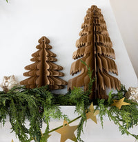 Two kraft paper Christmas trees styled on a mantel with greenery