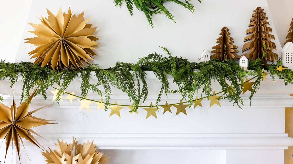 Kraft paper Christmas trees styled on a mantel with a star garland and greenery